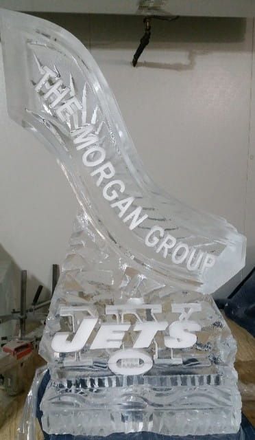Transparent trophy engraved “WILLIAM MORGAN GROUP” and “JETS” on a tabletop.
