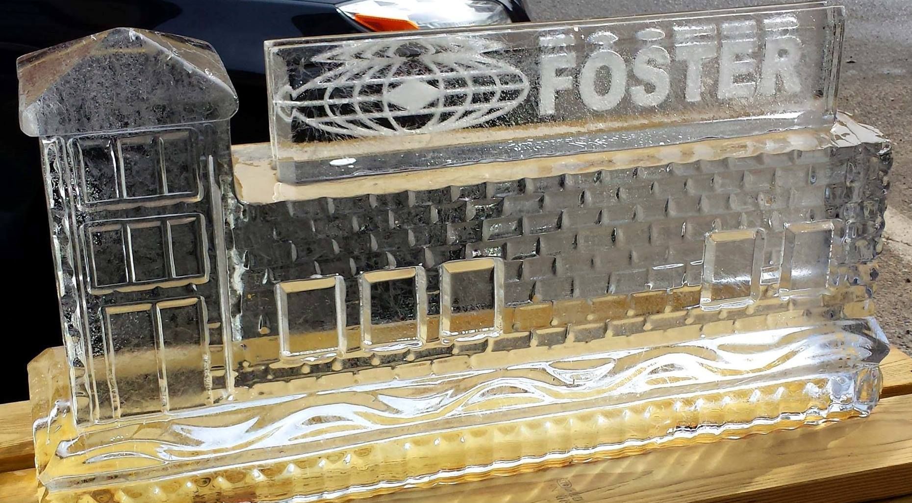 Clear acrylic model of a building with a tower and rooftop sign reading “FOSTER”