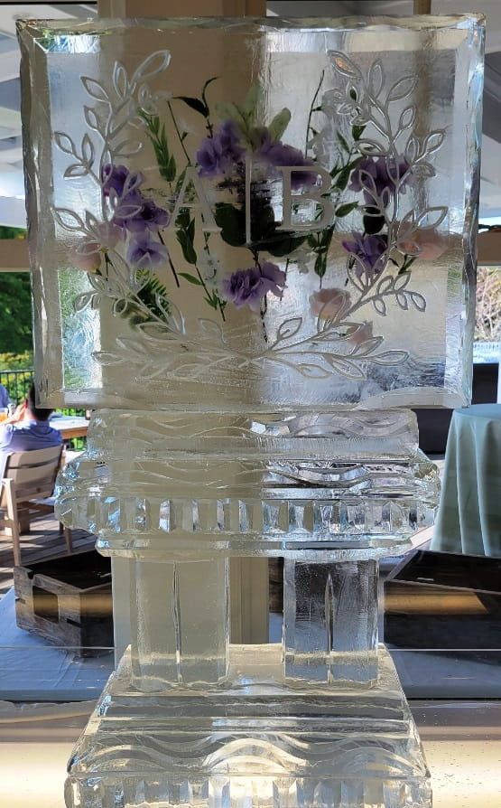 Clear glass vase with purple floral etching on a table, with a reflective patterned base