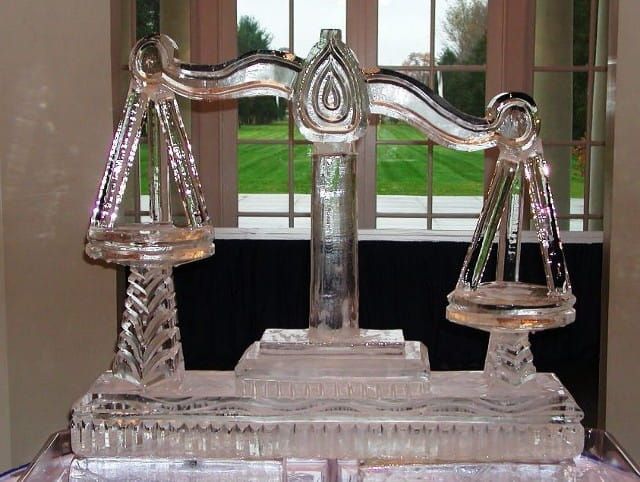 Glass scale figurine on a windowsill, with balanced pans and clear decorative details