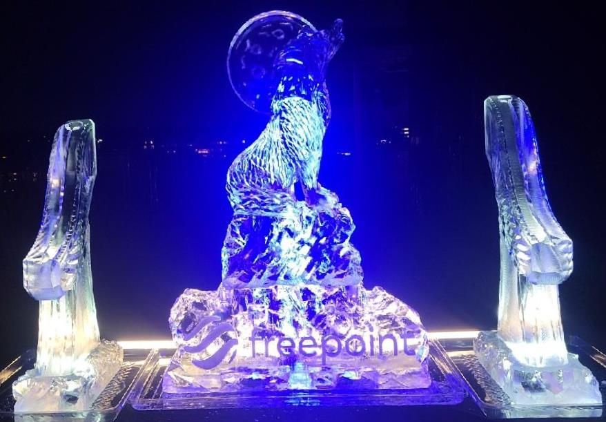 Blue-lit ice sculpture display with two tall side pillars and a central figure on a stage