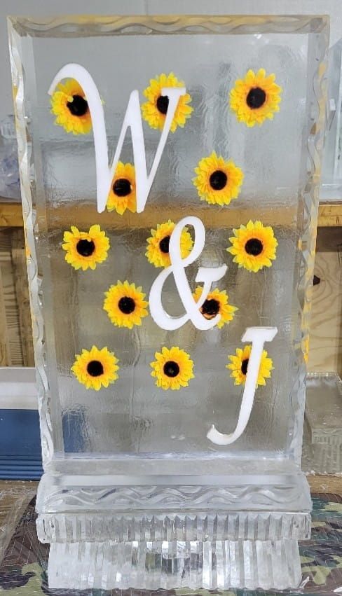 Clear glass block with white W & J monogram and yellow sunflower accents on a textured base