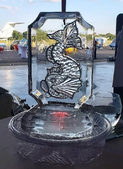 Clear ice sculpture with a rose design on a table at an outdoor event