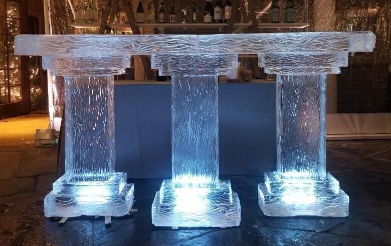 Three glowing ice pillars supporting a clear ice tabletop at night