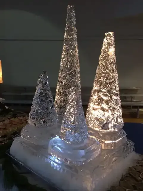Three illuminated glass cone decorations on a snowy base at night