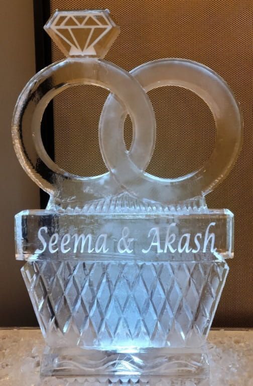 Clear glass decorative plaque with two rings and the engraved names “Seema & Akash”
