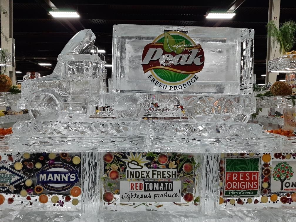 Ice sculpture of a Peak Fresh Produce crate display with surrounding fruit crates in a market setting