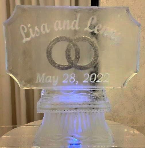 Engraved glass plaque with interlocking rings and the names Lisa and Lee, dated May 28, 2022.