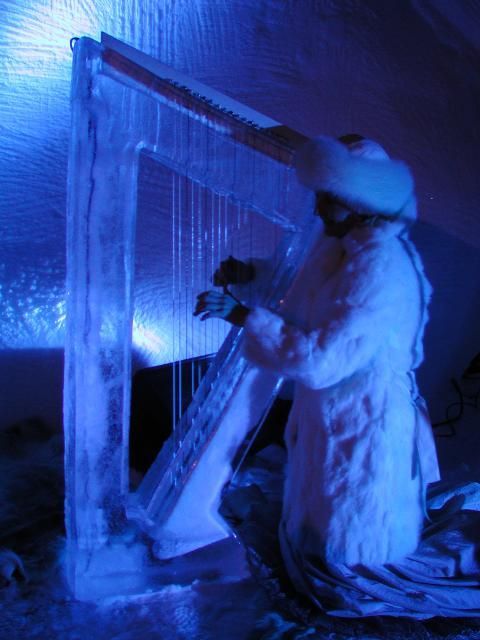 Ice sculptor carving a large translucent ice frame under blue light