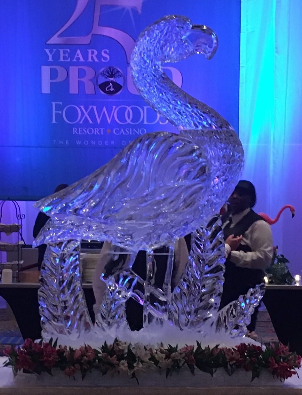 Crystal bird sculpture on a stage at Foxwoods Resort Casino with blue lighting and floral decorations