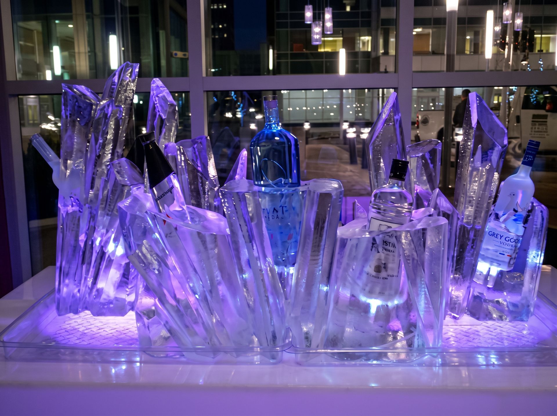 Purple-lit crystal ice sculpture display on a table in front of large windows