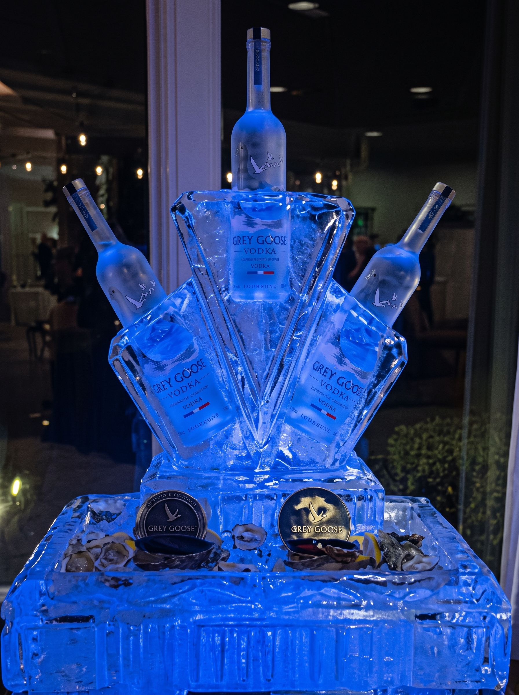 Blue ice sculpture resembling a throne with bottles and two skulls on a pedestal
