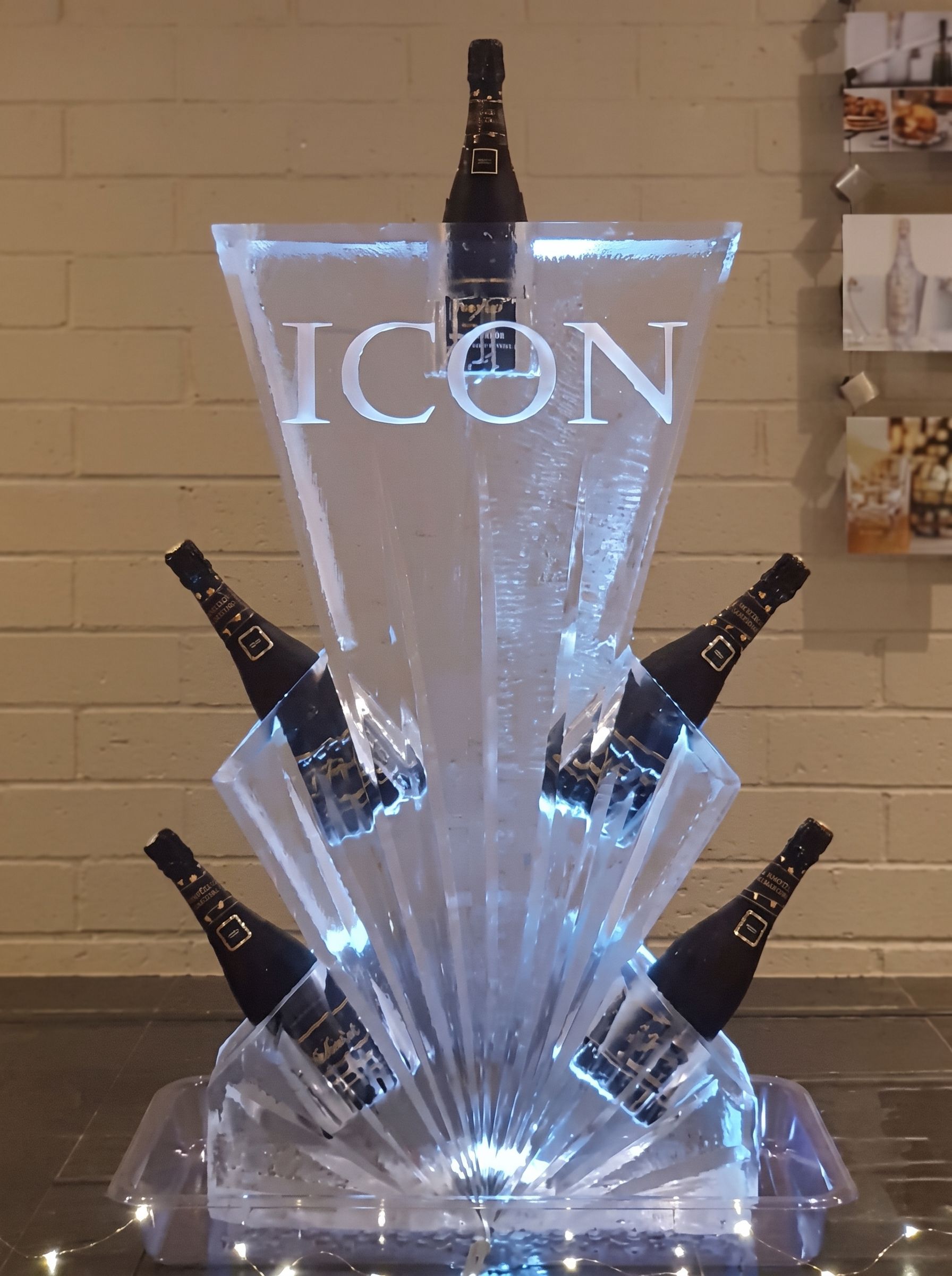 Illuminated martini-glass display with the word “ICON” and several bottles arranged around it.