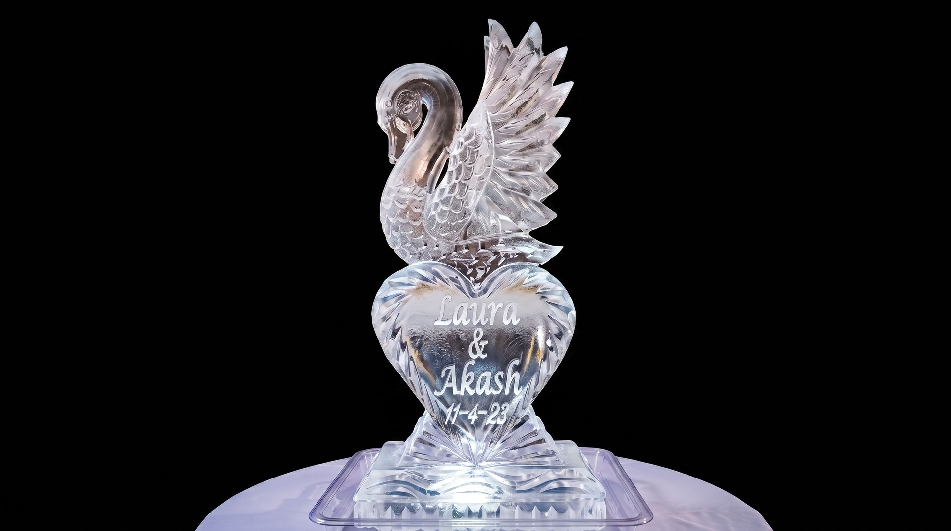 Clear glass swan trophy with wings raised on a black background