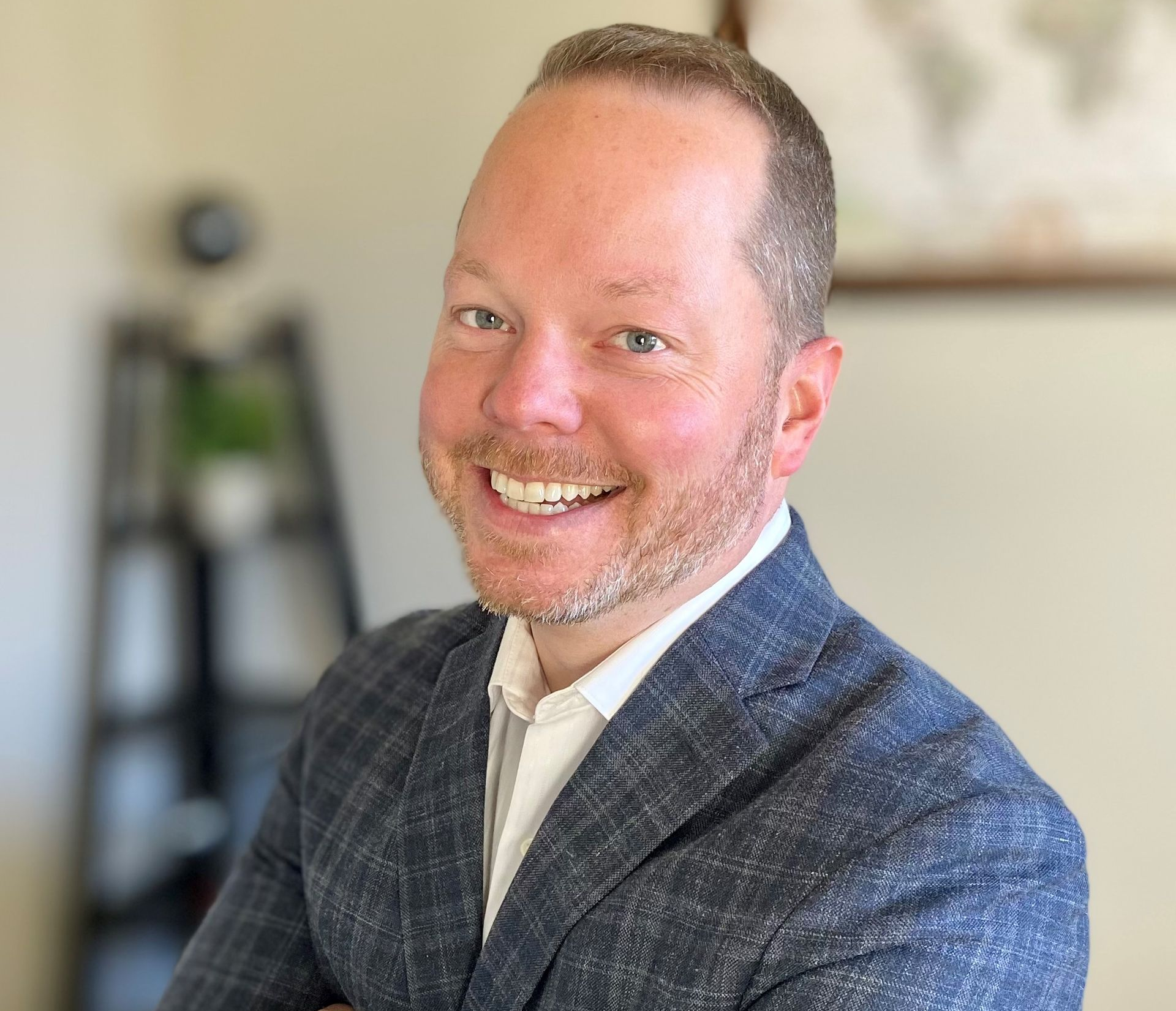 Man in a blue blazer smiles at the camera, arms crossed.