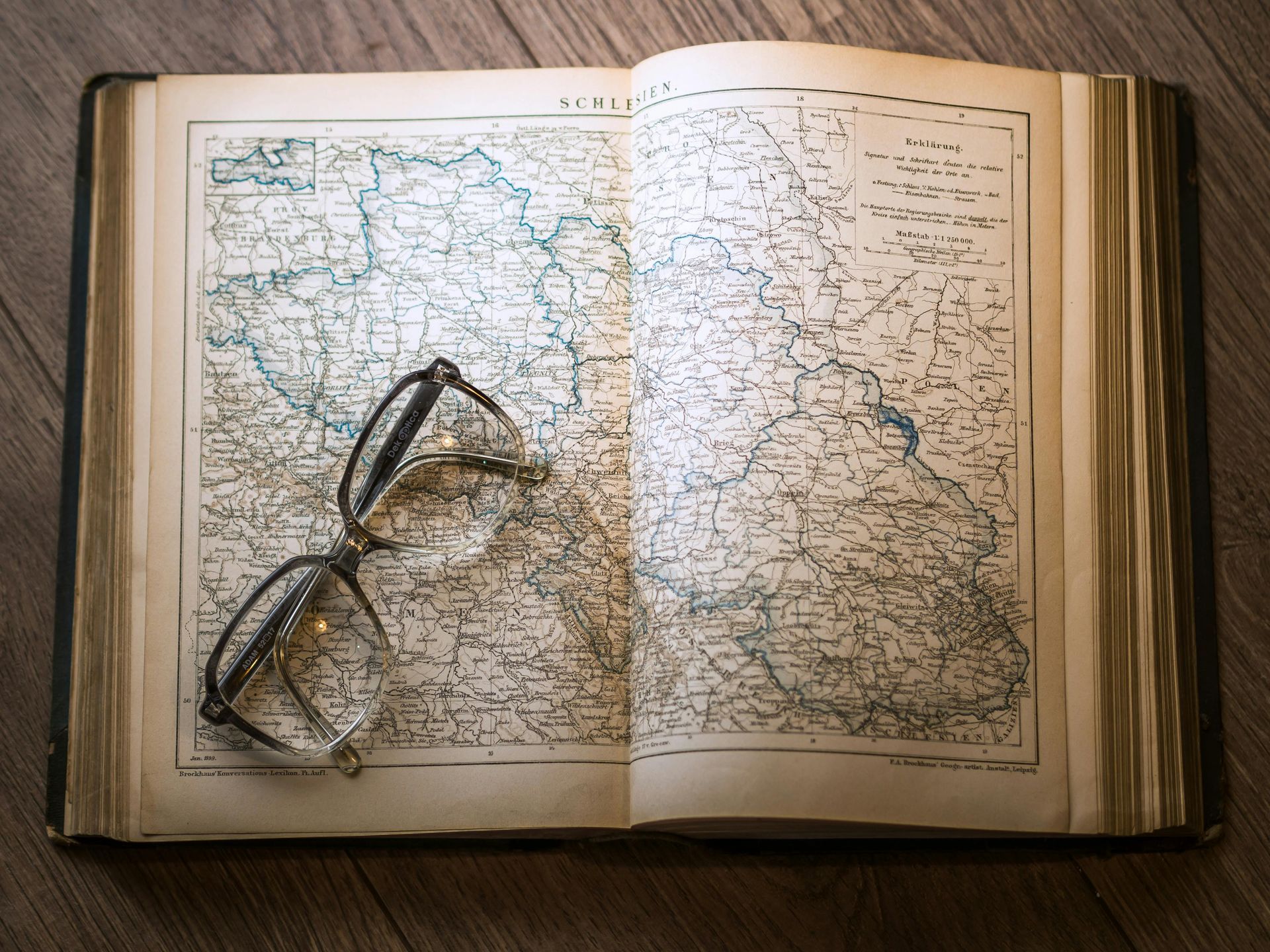 Open book with a detailed map, reading glasses resting on the pages.