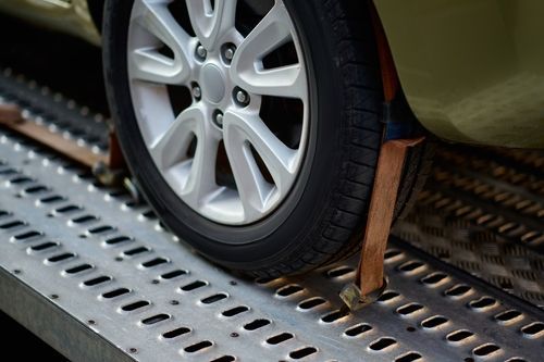 Car tire secured with wheel chocks on a metal test track or conveyor platform