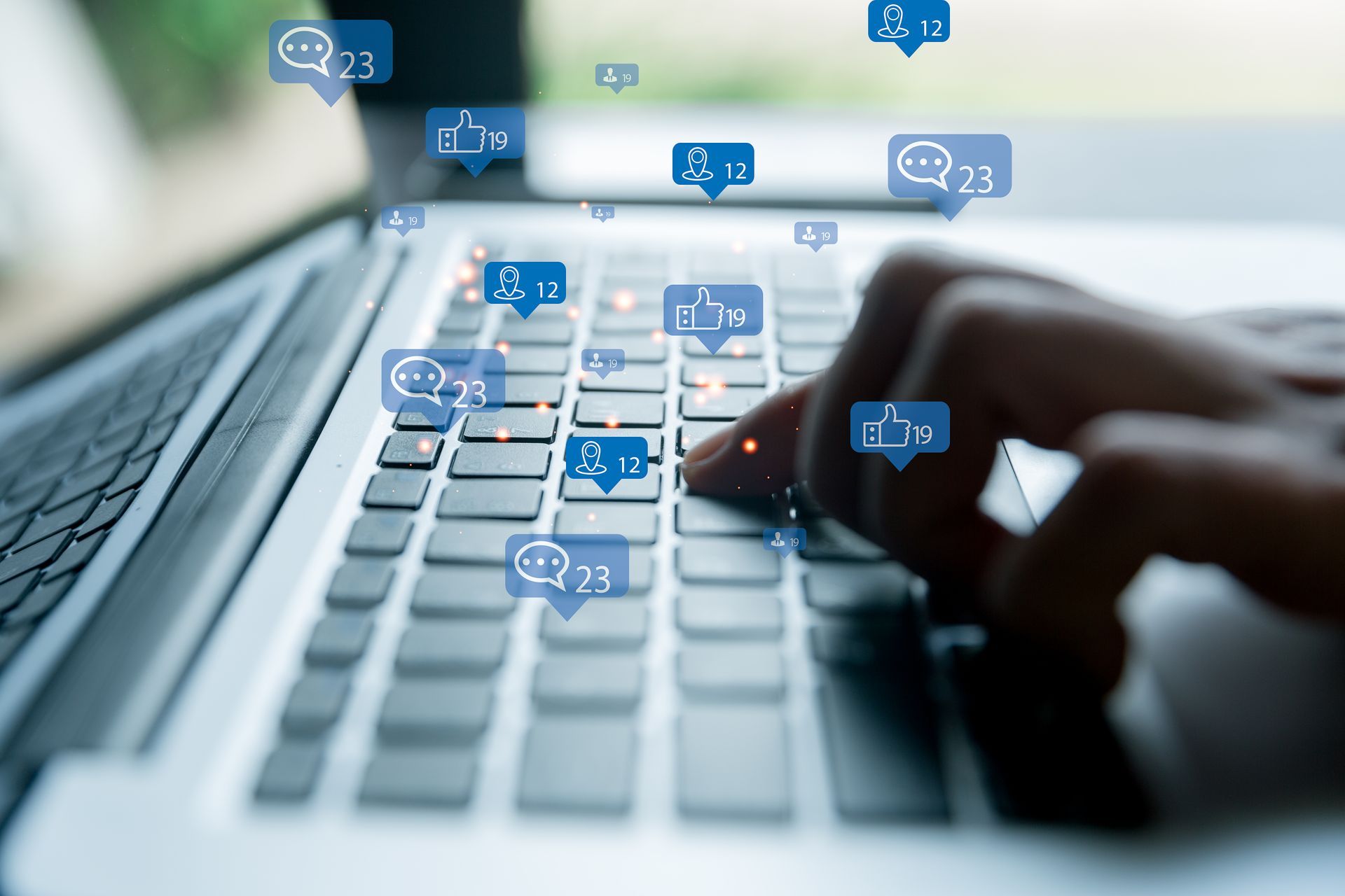 Mani che digitano sulla tastiera di un laptop, con icone blu di chat sospese sopra