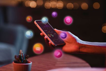 Una mano tiene in mano uno smartphone, con icone luminose delle app