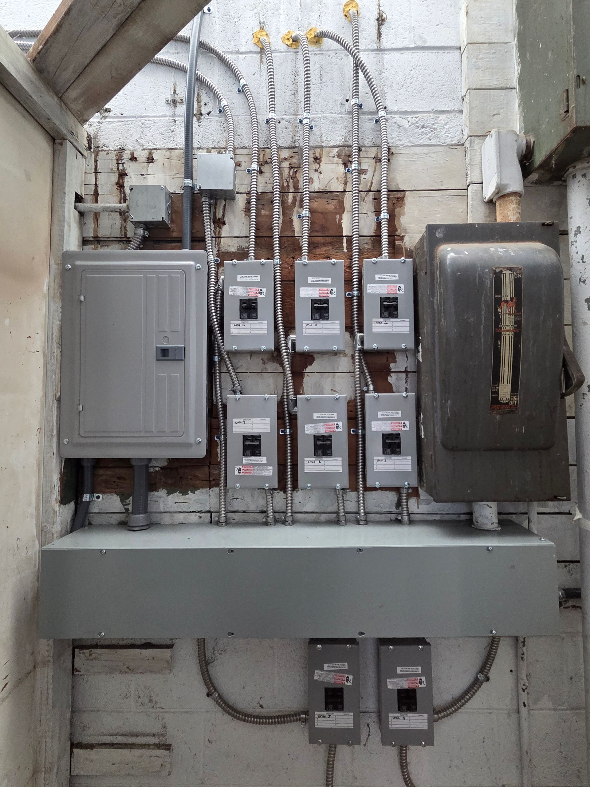 Electrical meter and breaker panel wall with multiple utility boxes and exposed wiring