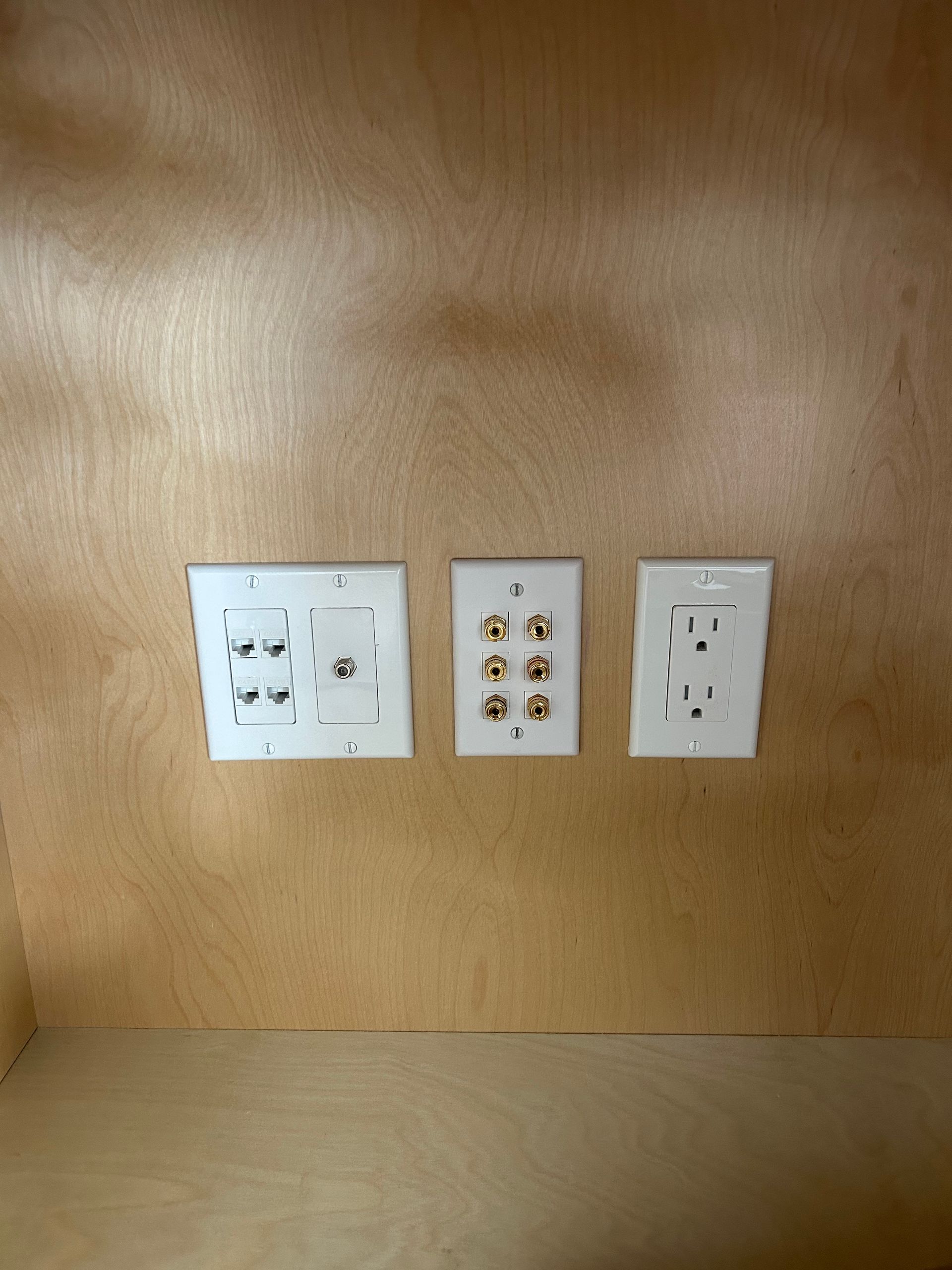 Three wall-mounted outlet and light switch plates on a wood-paneled wall.
