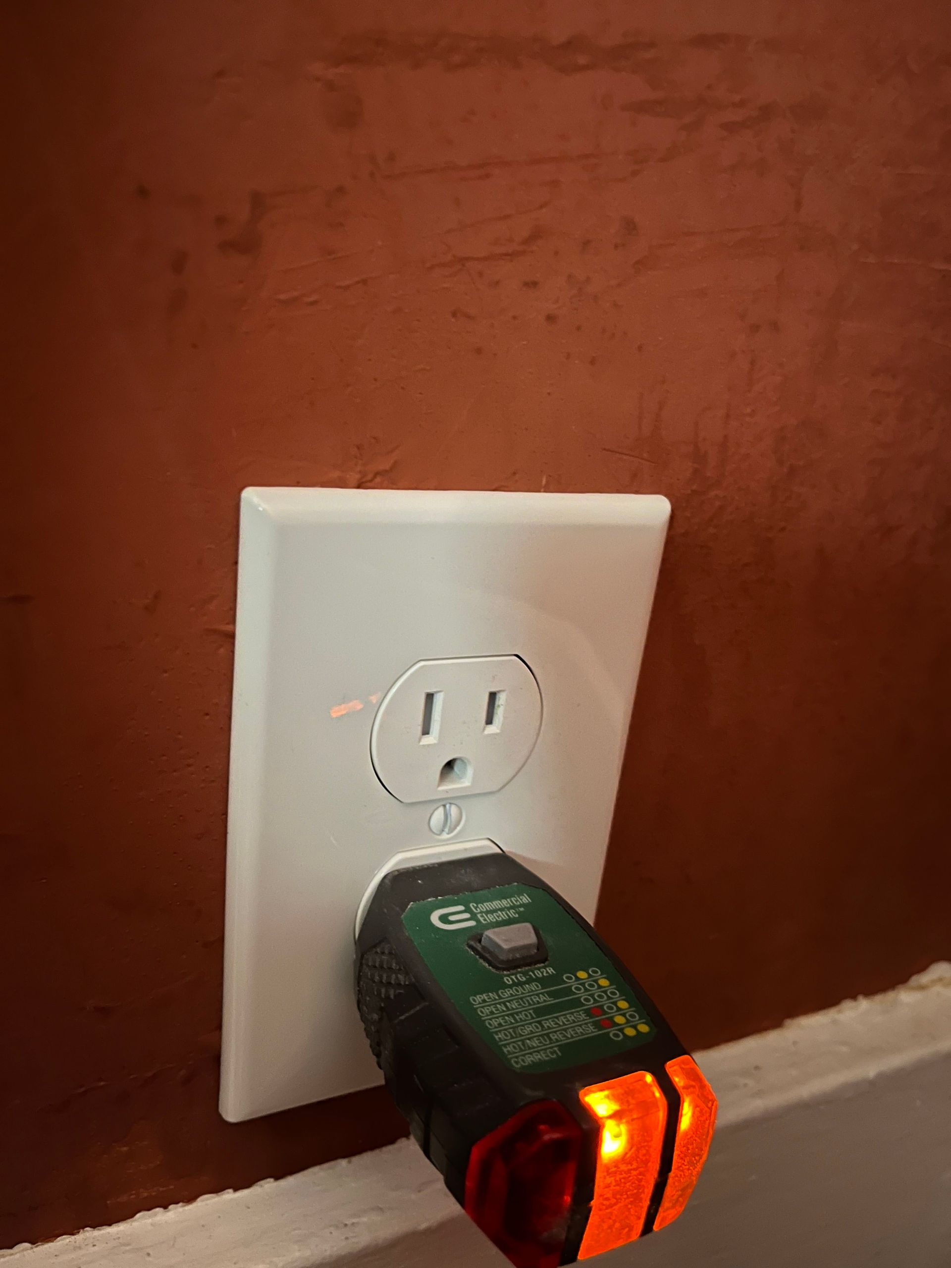 Nightlight plugged into a white wall outlet on a red wall.