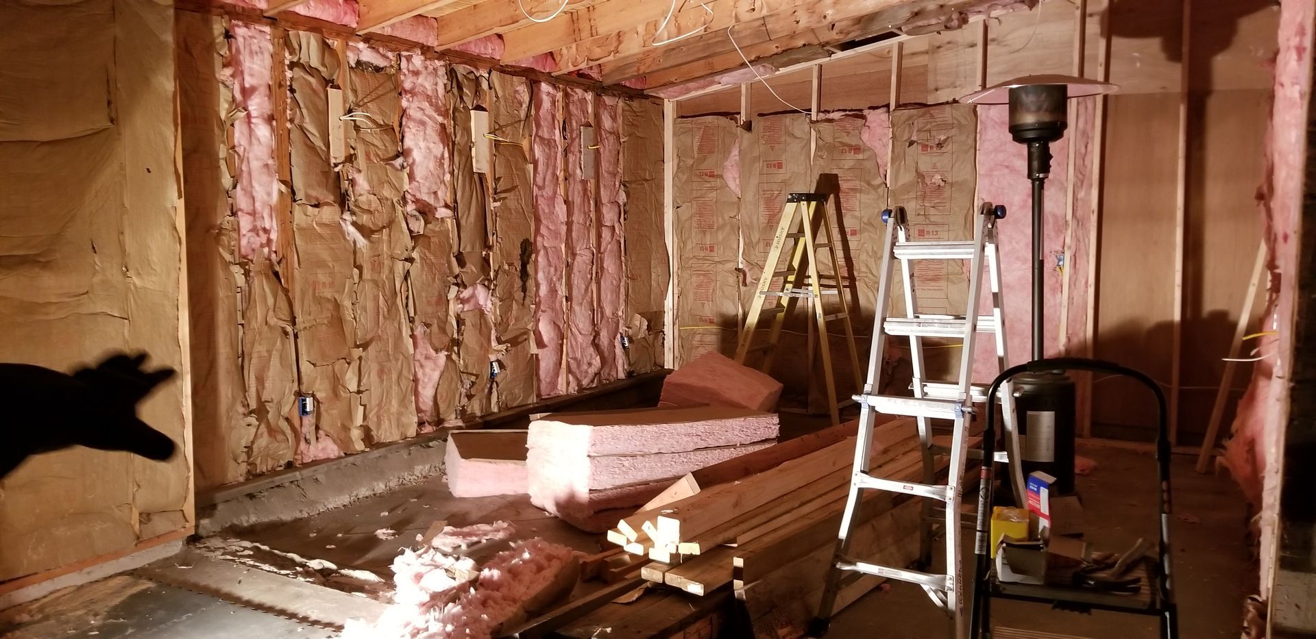 A room with a ladder and a light on the floor.