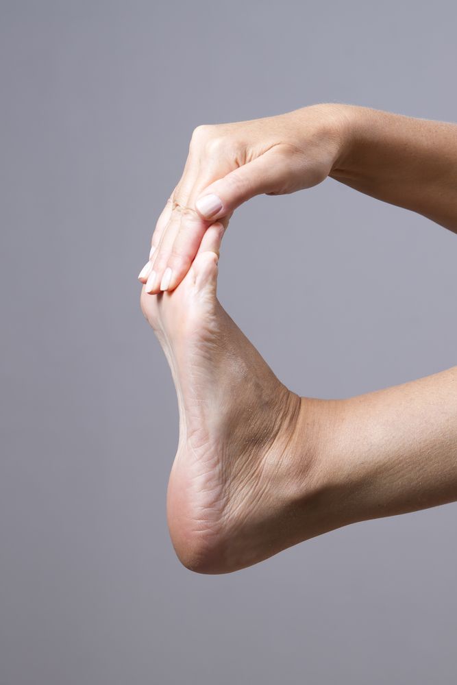 A Woman Is Stretching Her Foot With Her Hands Mooloolaba Foot Centre In Mooloolaba, QLD