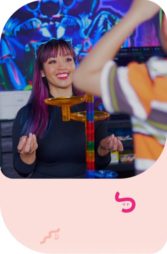 Woman smiling at a colorful arcade game with a glowing neon backdrop