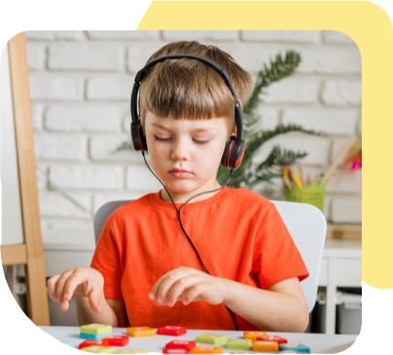 Child wearing headphones, focused on a colorful activity at a table in a bright room