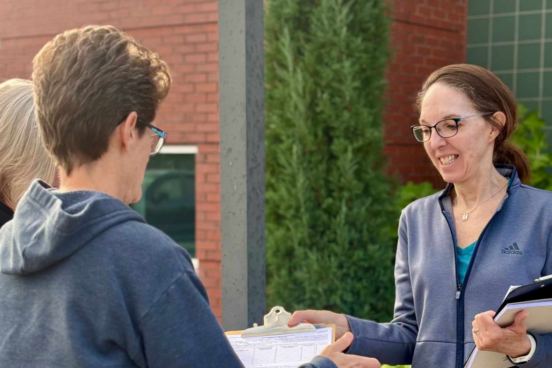 Julie Fortier hands a petition to two supporters.