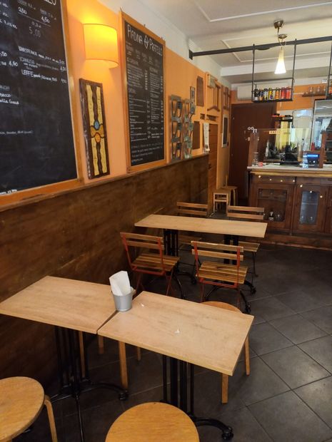 Un accogliente caffè vuoto con tavoli e sedie in legno e lavagne con i menù lungo la parete.