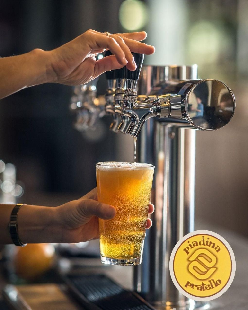 Una persona versa a mano una birra da un rubinetto cromato in un bicchiere schiumoso