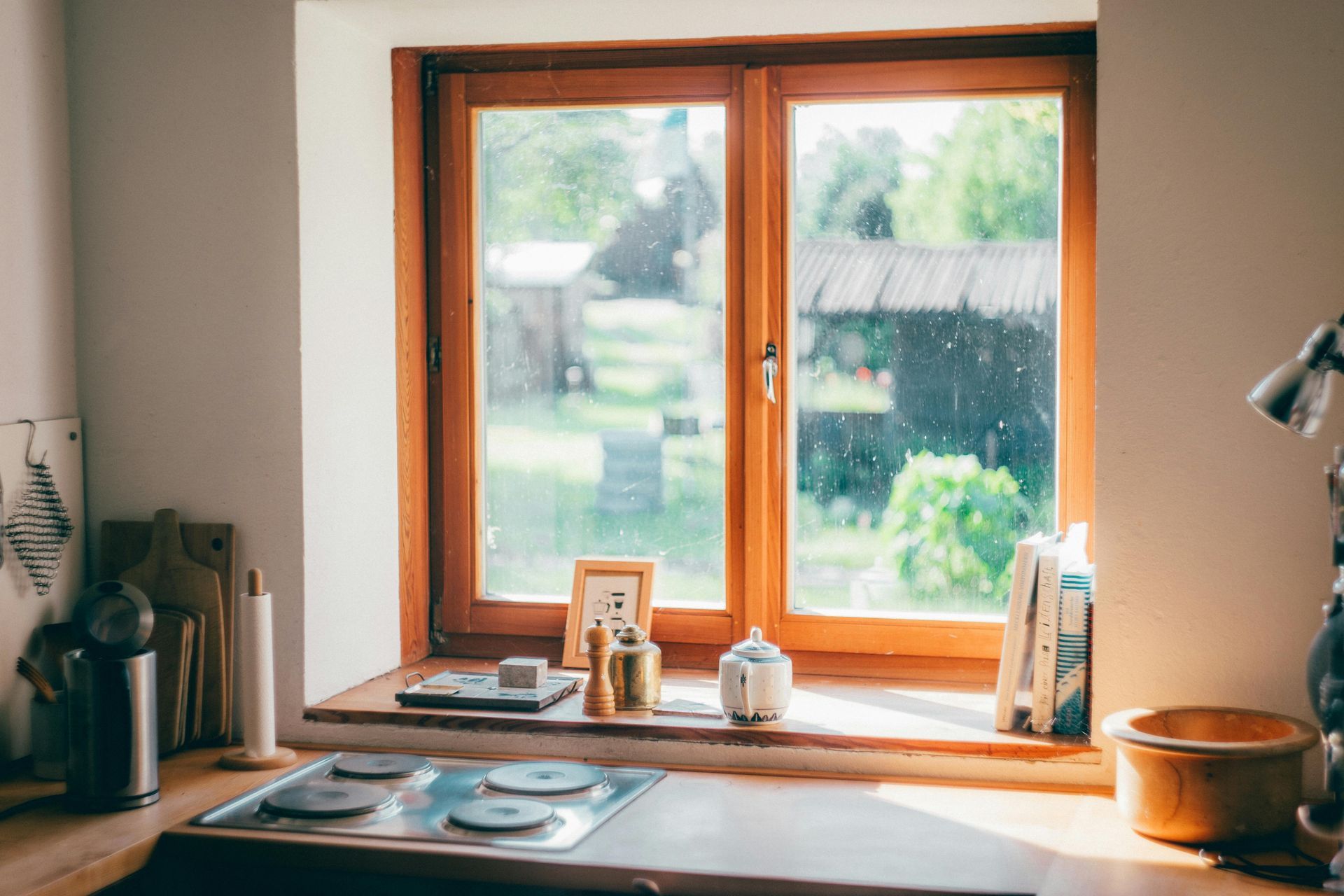 Cozy kitchen window with wooden sill, sink, and small decor overlooking a green garden