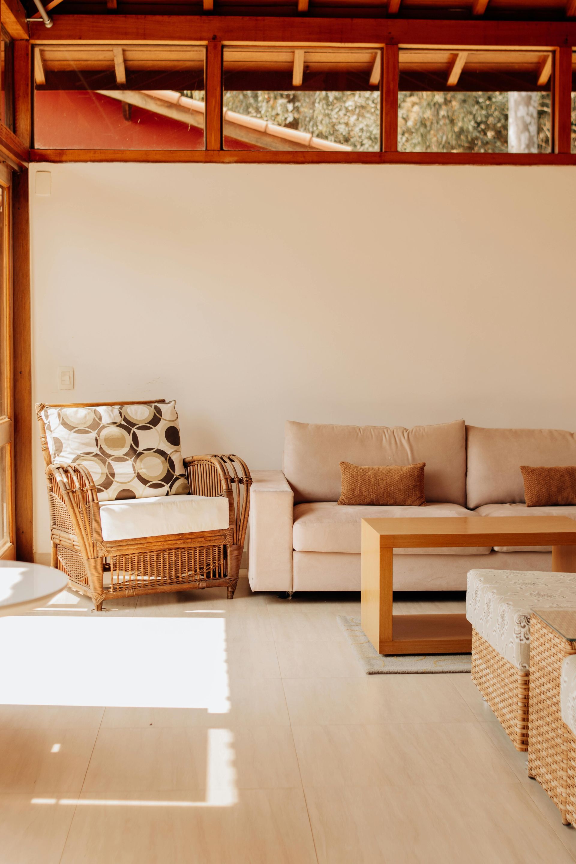 Bright living room with wicker and beige sofas, wooden coffee table, and sunlight on the floor