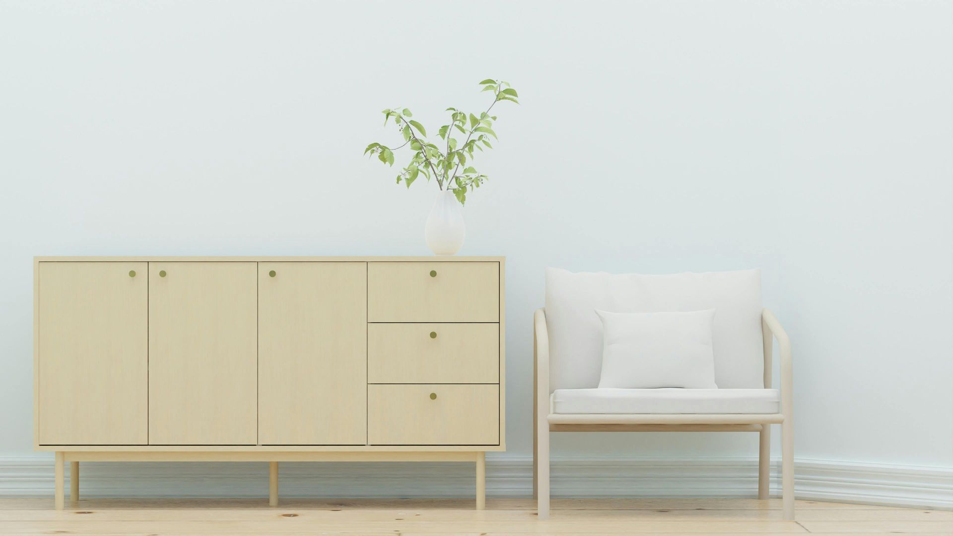 Minimalist room with a light wood cabinet, white armchair, and small plant against a pale wall.