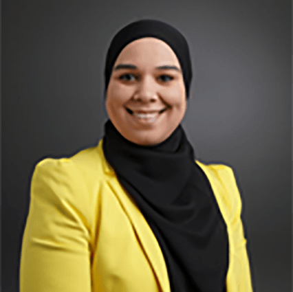 Vrouw met zwarte hijab en gele blazer lacht.