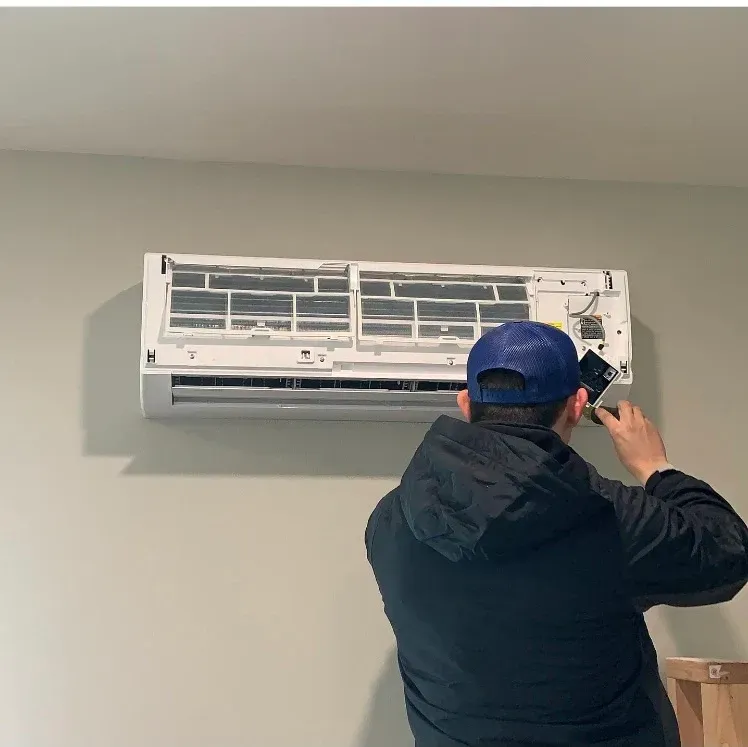 Person cleaning a wall-mounted air conditioner with the front cover open