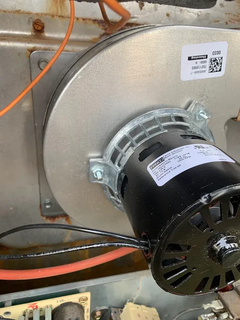 Close-up of a furnace blower motor and wiring inside a metal HVAC unit.