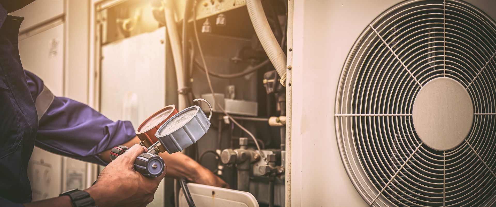 A technician using a pressure gauge to check an HVAC system.