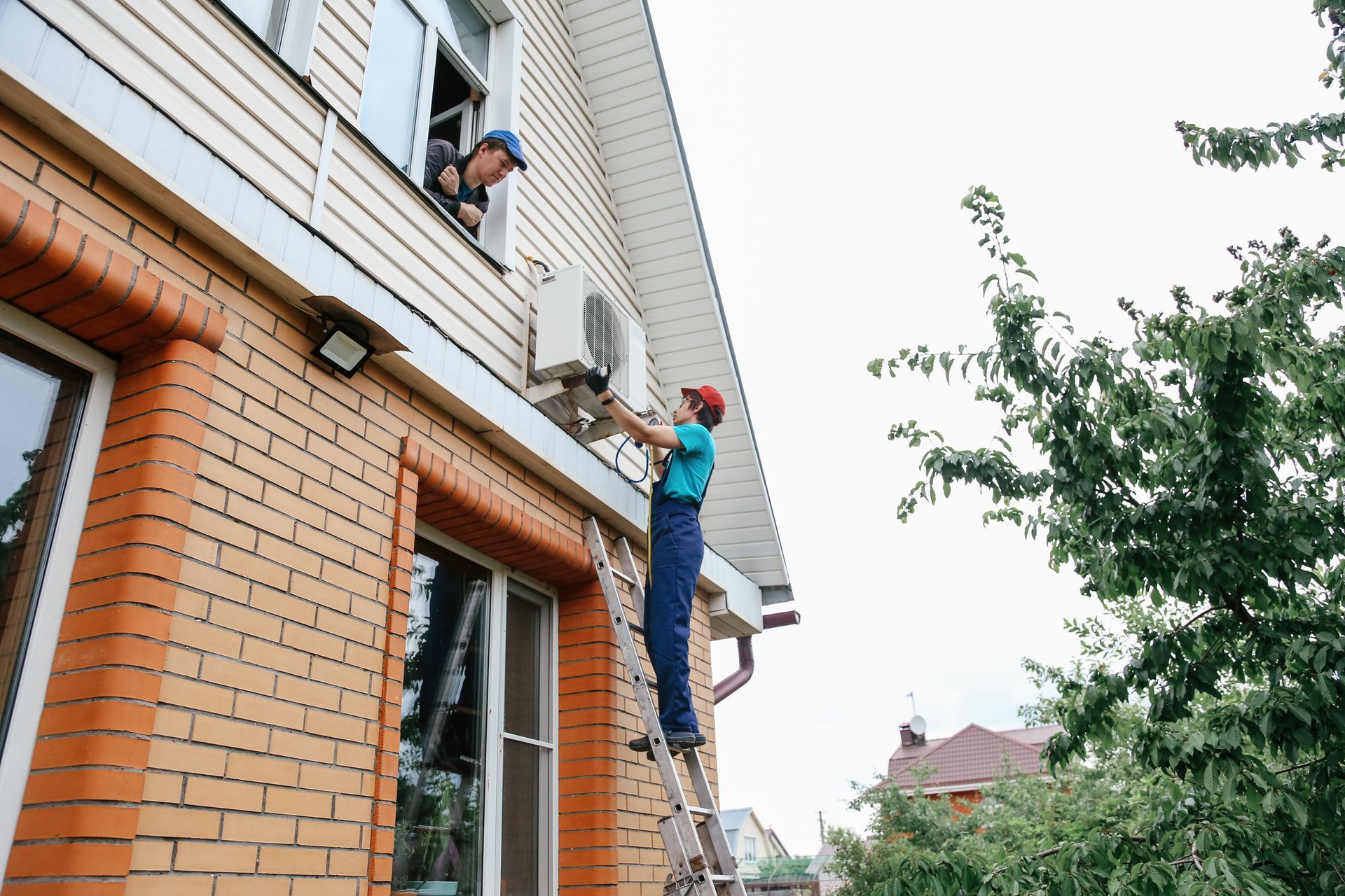 Mid Adult Man Doing Home Routine, Repairing Air-Conditioner Outdoor And Using Folding Ladder