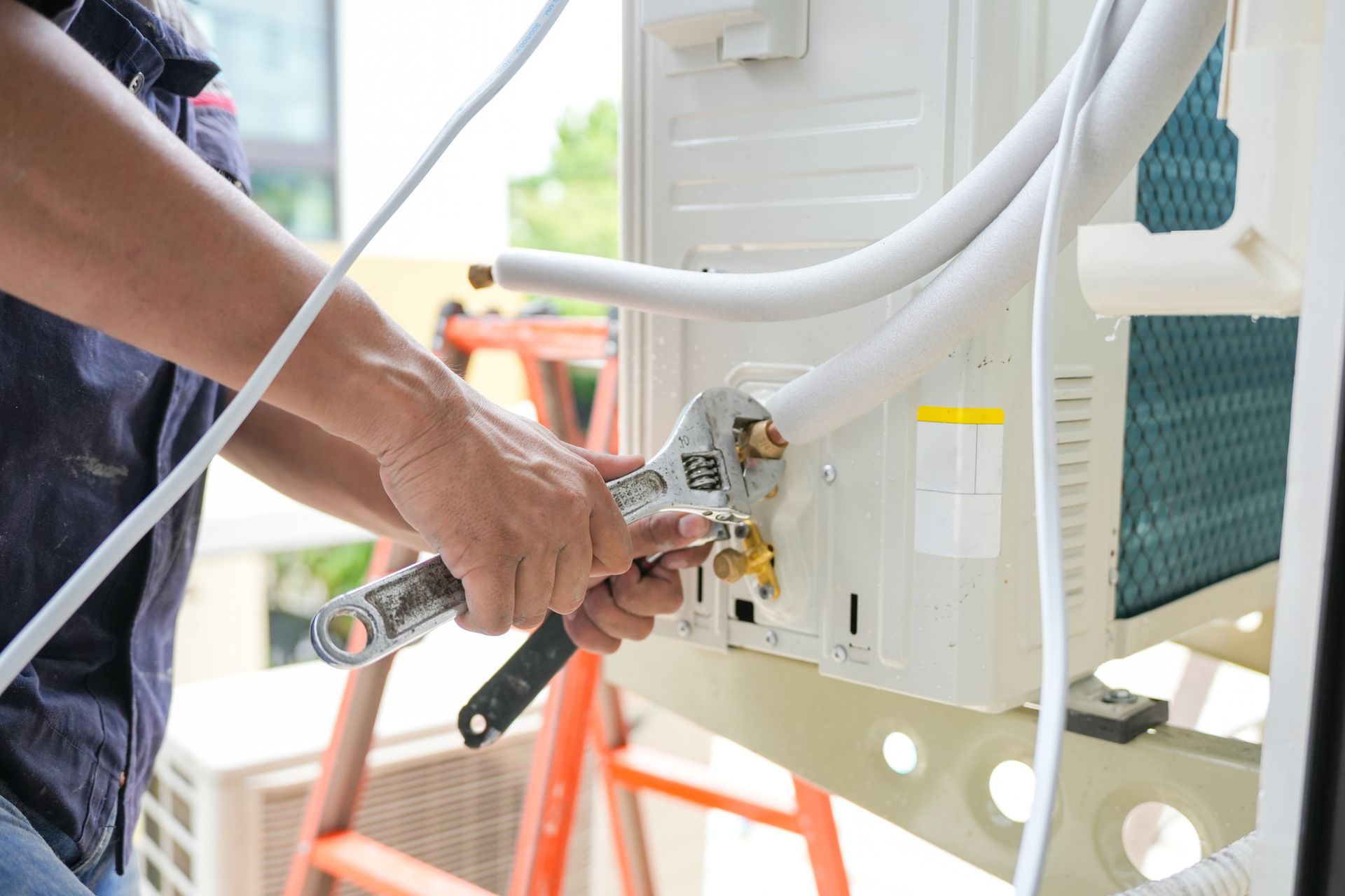HVAC technician tightening air conditioner lines during professional AC repair service.