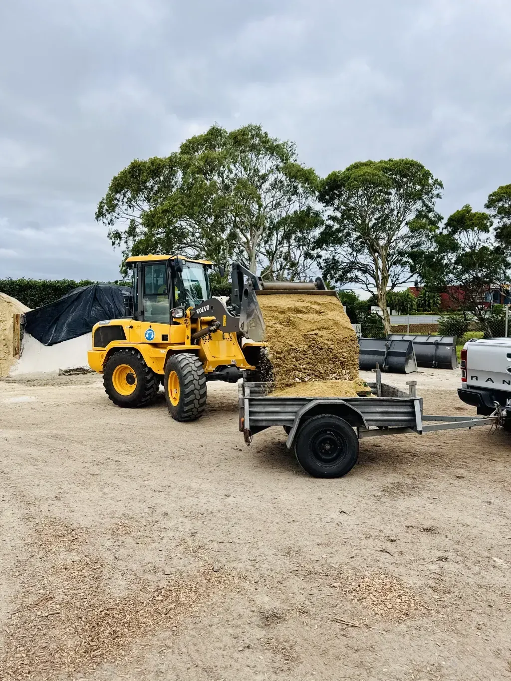 A bulldozer is loading dirt onto a trailer.