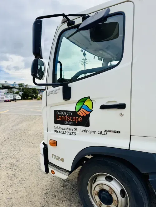 A white garden city landscape centre truck is parked on gravel.