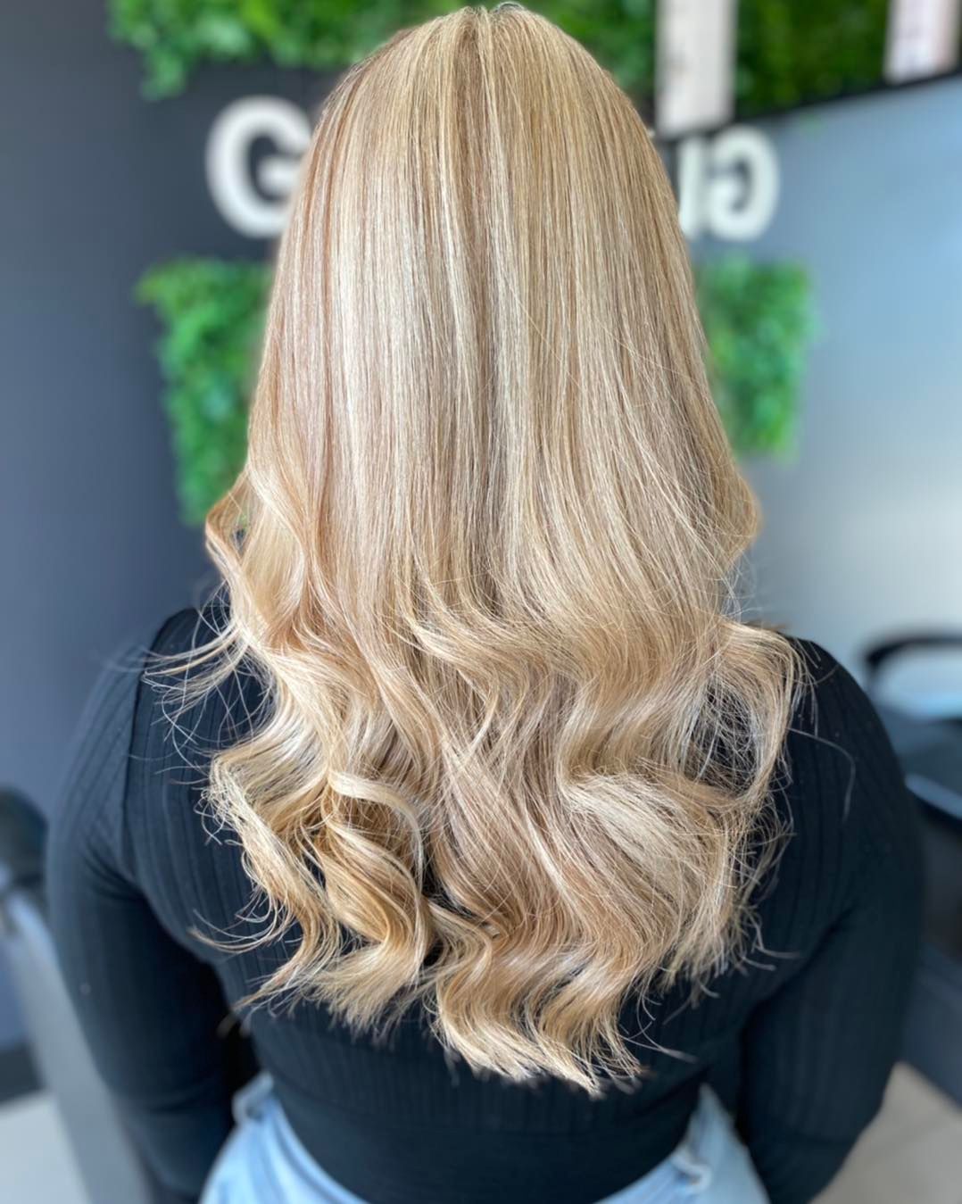 A Woman With Long Blonde Hair is Wearing a Black Shirt and Jeans — Glam Hair and Beauty in Woy Woy, NSW