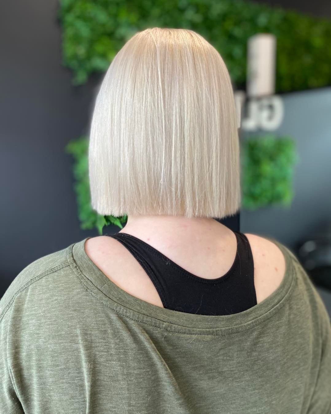 A Woman With Blonde Hair is Wearing a Green Shirt and a Black Tank Top — Glam Hair and Beauty in Woy Woy, NSW