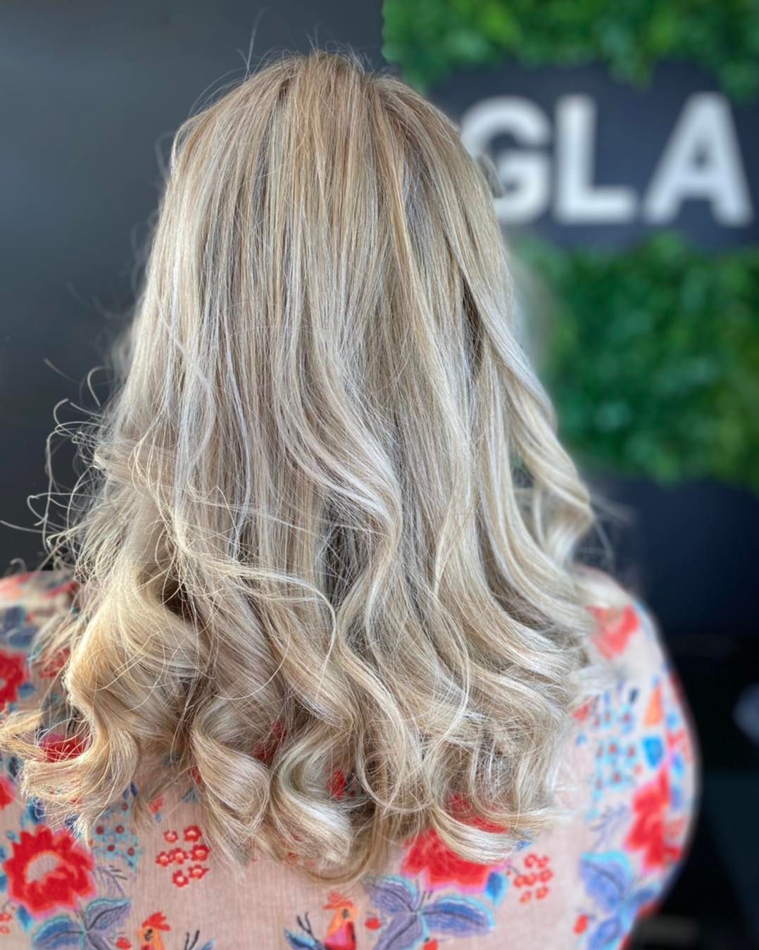 A Woman With Long Blonde Hair is Wearing a Floral Shirt — Glam Hair and Beauty in Woy Woy, NSW