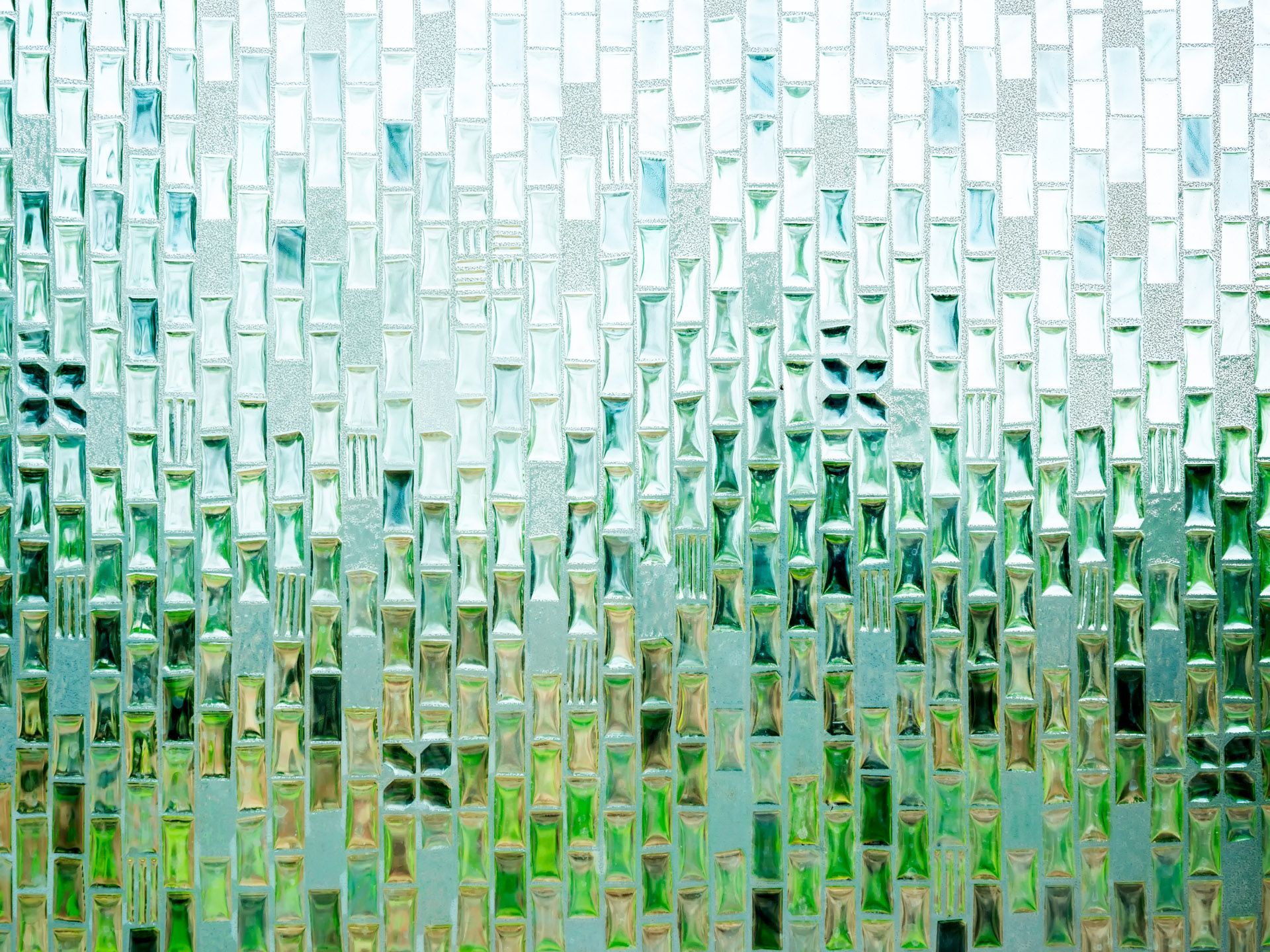 Abstract mosaic of green and white glass-like tiles forming a textured pattern