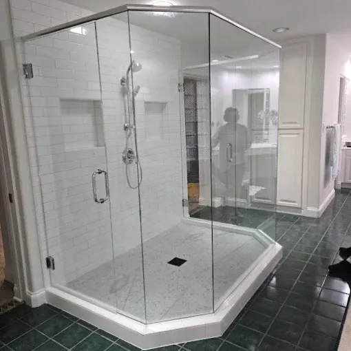 Glass walk-in shower with white tile walls and dark green floor tiles in a bathroom