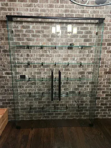 Glass fireplace doors in a brick wall with dark wood flooring and two wall lights above
